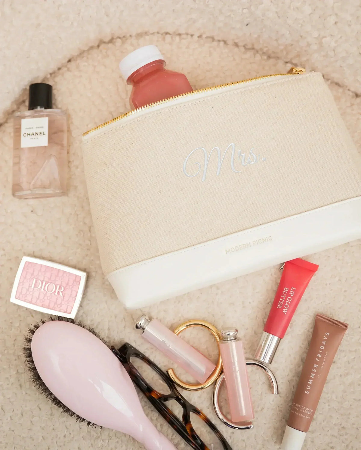Beige canvas pouch with 'Mrs.' embroidery, styled with beauty products and accessories for chic everyday use.