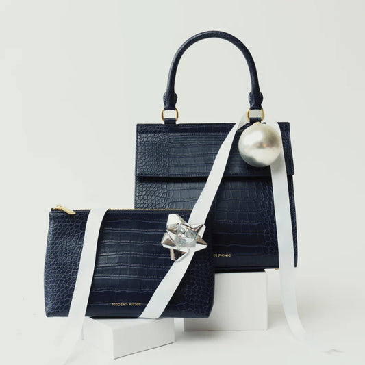 Navy blue vegan leather tote and pouch with crocodile texture, decorated with ribbon and ornaments.