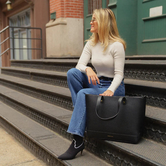 Woman in casual outfit sitting on steps with large black insulated tote bag