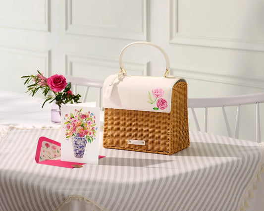 Chic woven insulated lunch bag with floral accents on table, next to flower and greeting card