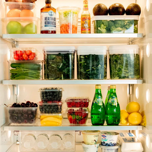 Organized fridge with fresh fruits, vegetables, sparkling water, and yogurt containers.