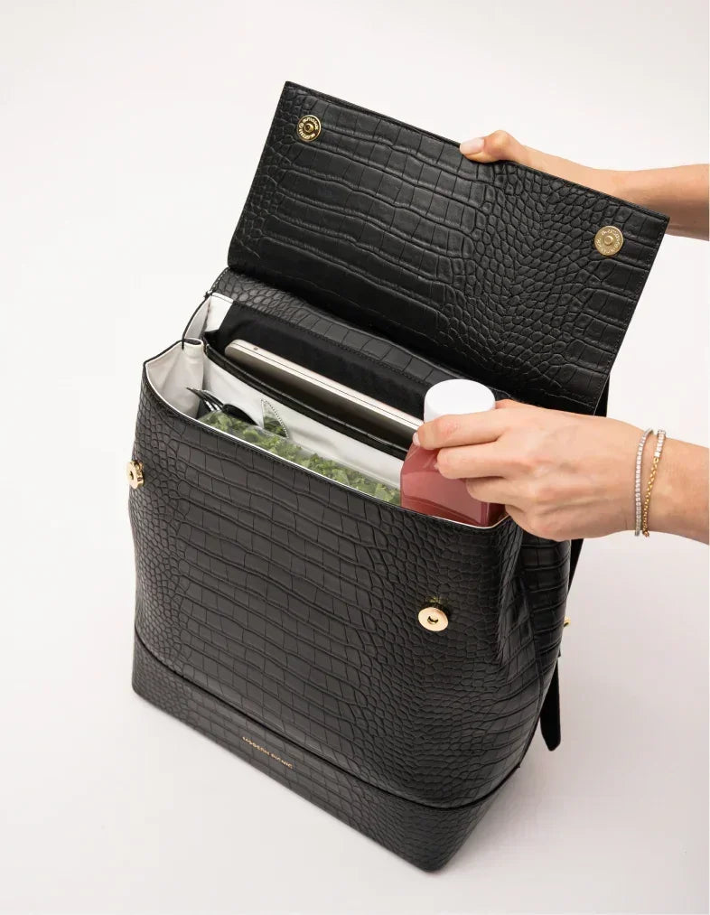 Black croc-texture insulated lunch tote with gold hardware, holding salad and drink, perfect for work or travel.