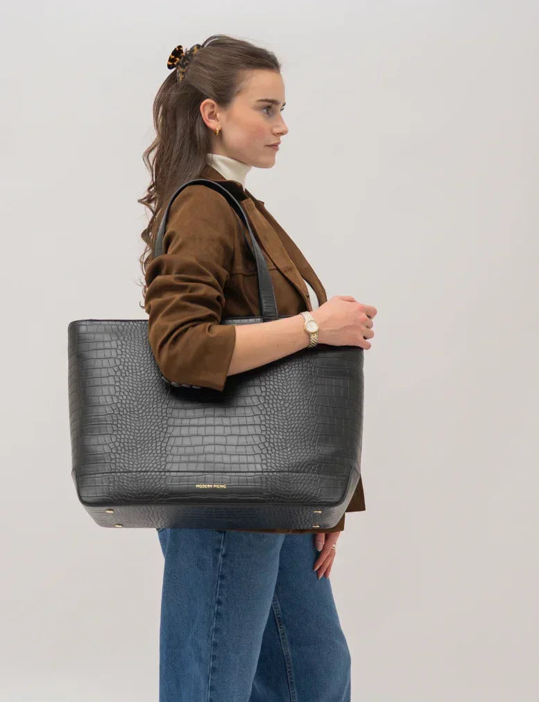 Woman holding black croc-texture vegan leather tote bag, stylish for work or travel