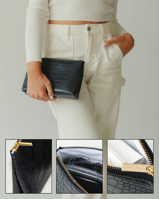 Woman holding a black crocodile-texture vegan leather insulated lunch clutch with gold zipper