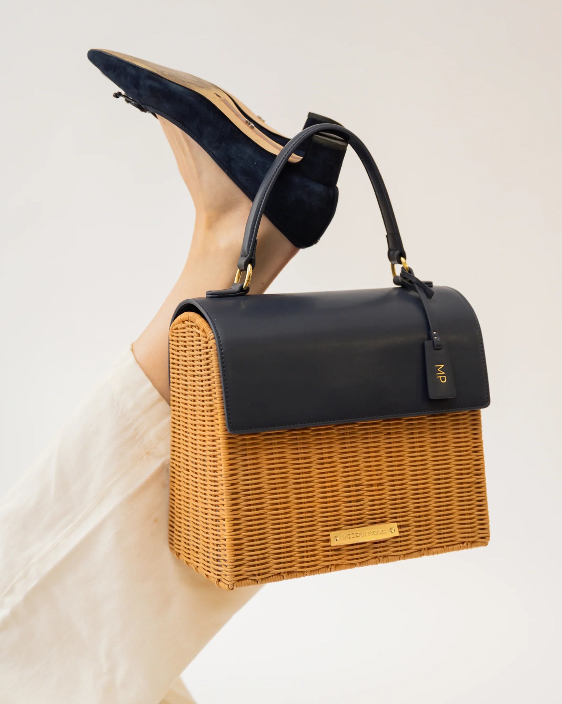 Stylish woven tote with black vegan leather top, paired with navy suede heels, perfect for modern professional style.