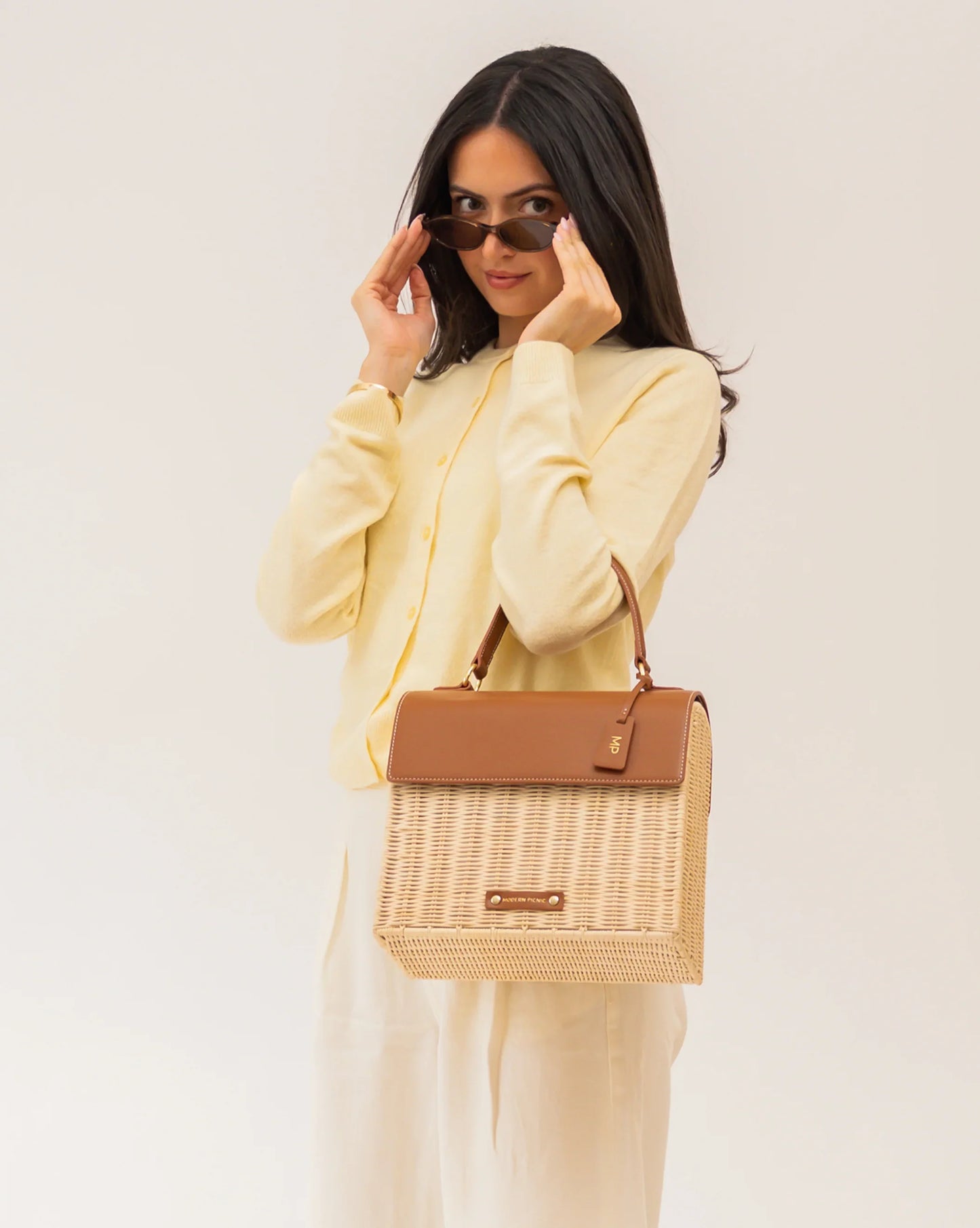 Stylish woman holding a chic woven tote bag with vegan leather accents, perfect for work or travel.