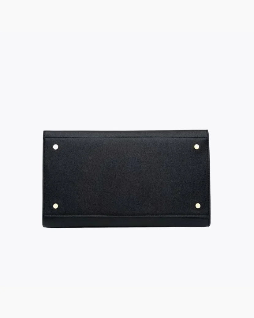 A close-up, straight-on product shot of the bottom of a black handbag. The image clearly shows the base, which is reinforced with four small gold-tone metal feet/studs for protection.