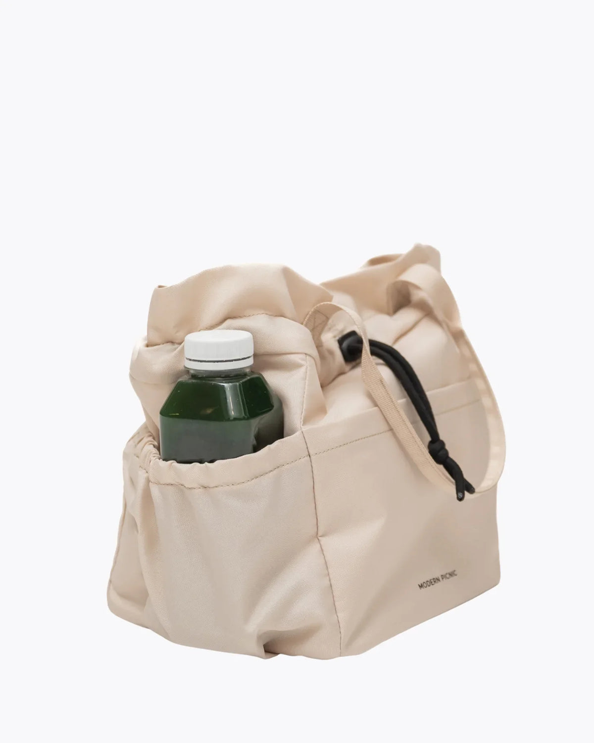 Cream insulated lunch tote bag with a green juice bottle inside.