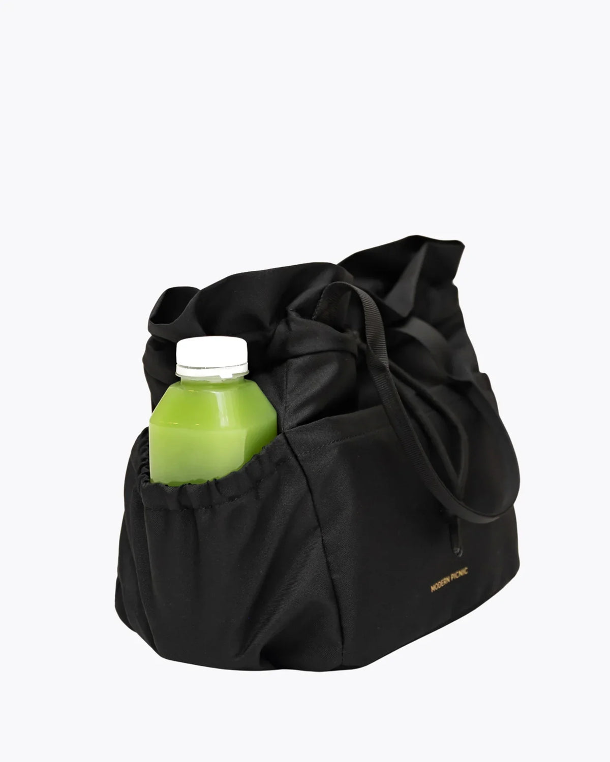 Black insulated lunch bag with a green juice bottle tucked into a side pocket.