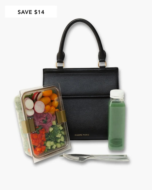 Stylish black insulated lunch bag with fresh salad, green juice, and utensils for healthy on-the-go meals.