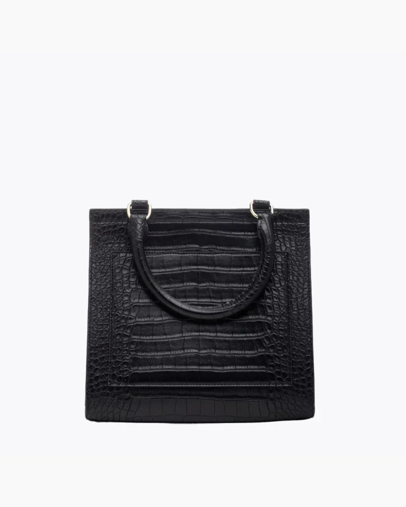 A close-up studio shot showing the back view of a structured black handbag. The bag is made of crocodile-embossed vegan leather and features a stitched-in slip pocket outline and a single curved top handle attached with gold hardware.
