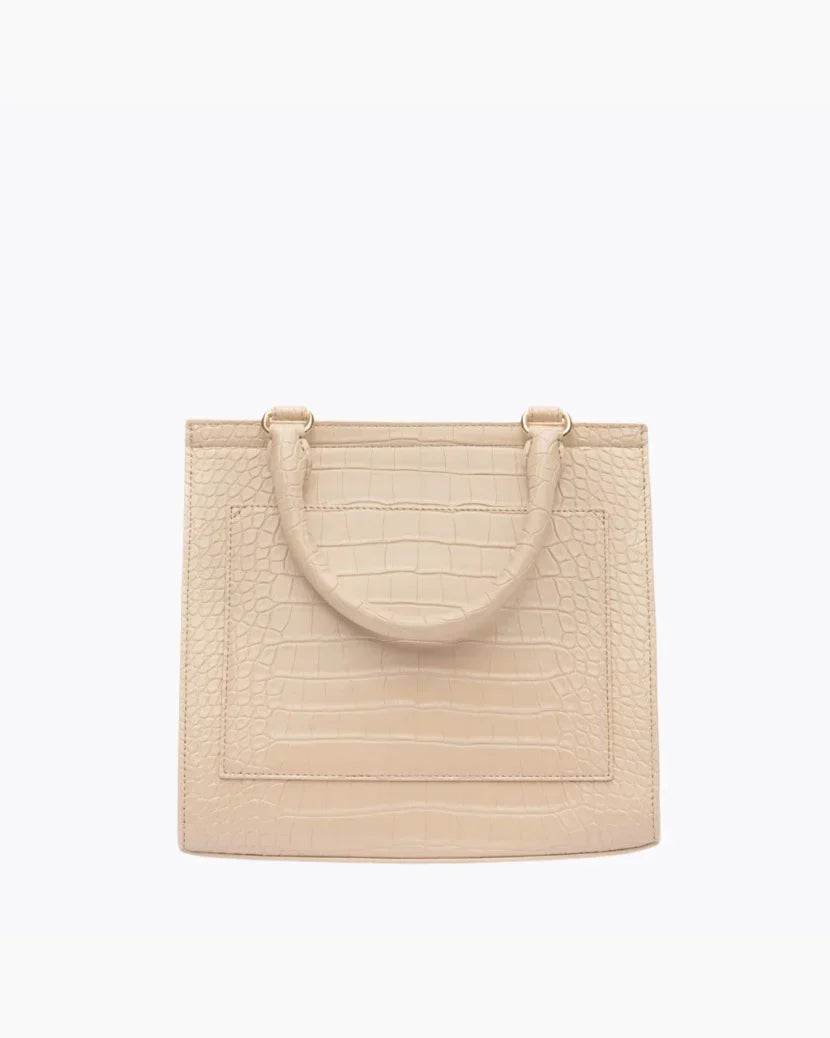 A close-up studio shot showing the back view of a structured light beige handbag. The bag is made of crocodile-embossed vegan leather and features a stitched-in slip pocket outline and a single curved top handle attached with gold hardware.