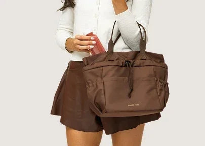 Woman carrying a large brown insulated tote bag for work or travel.