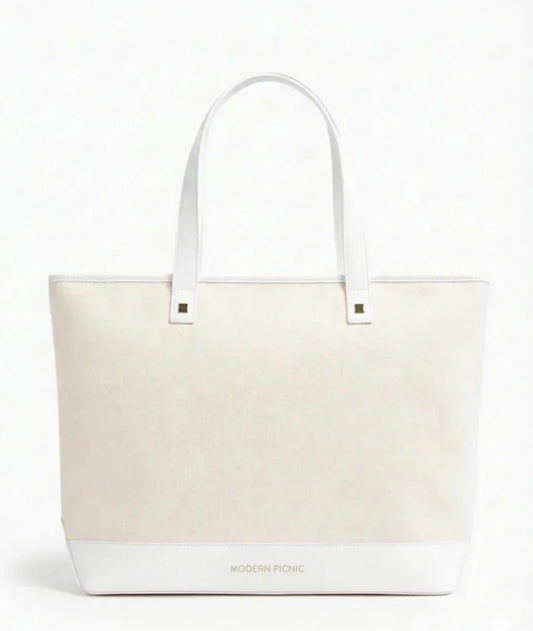 Cream canvas tote bag with white leather handles and base, featuring minimalist design for everyday use.