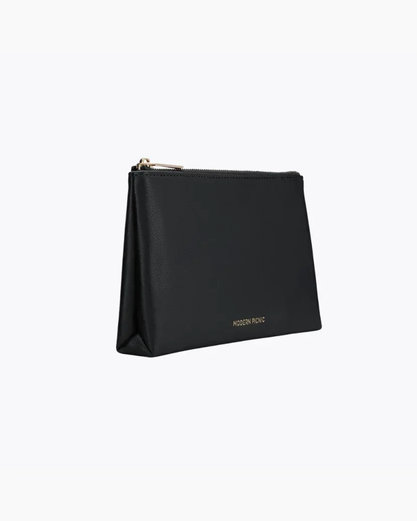 A three-quarter studio shot of a small black zippered pouch with a pebbled texture. The bag has a gold zipper and a visible gold "MODERN PICNIC" logo along the base.