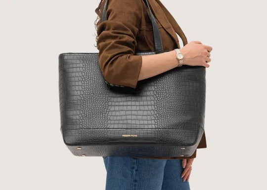 Woman carrying a black croc-embossed vegan leather insulated tote bag.