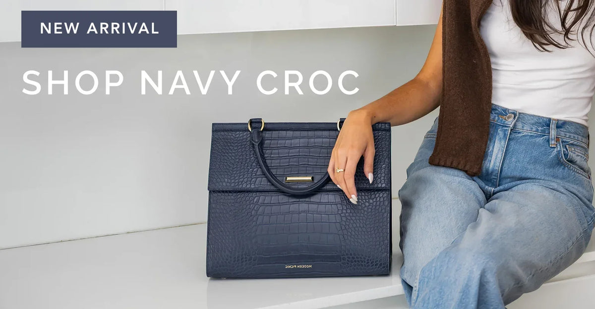 Navy blue crocodile embossed vegan leather tote bag held by a woman.