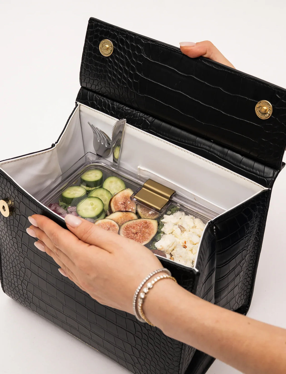 Black crocodile embossed vegan leather insulated lunch bag with healthy salad and figs inside.