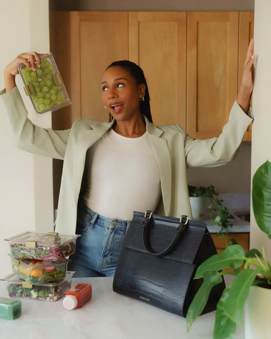 Stylish black insulated lunch tote with vegan leather texture, perfect for work or travel, paired with meal prep containers.