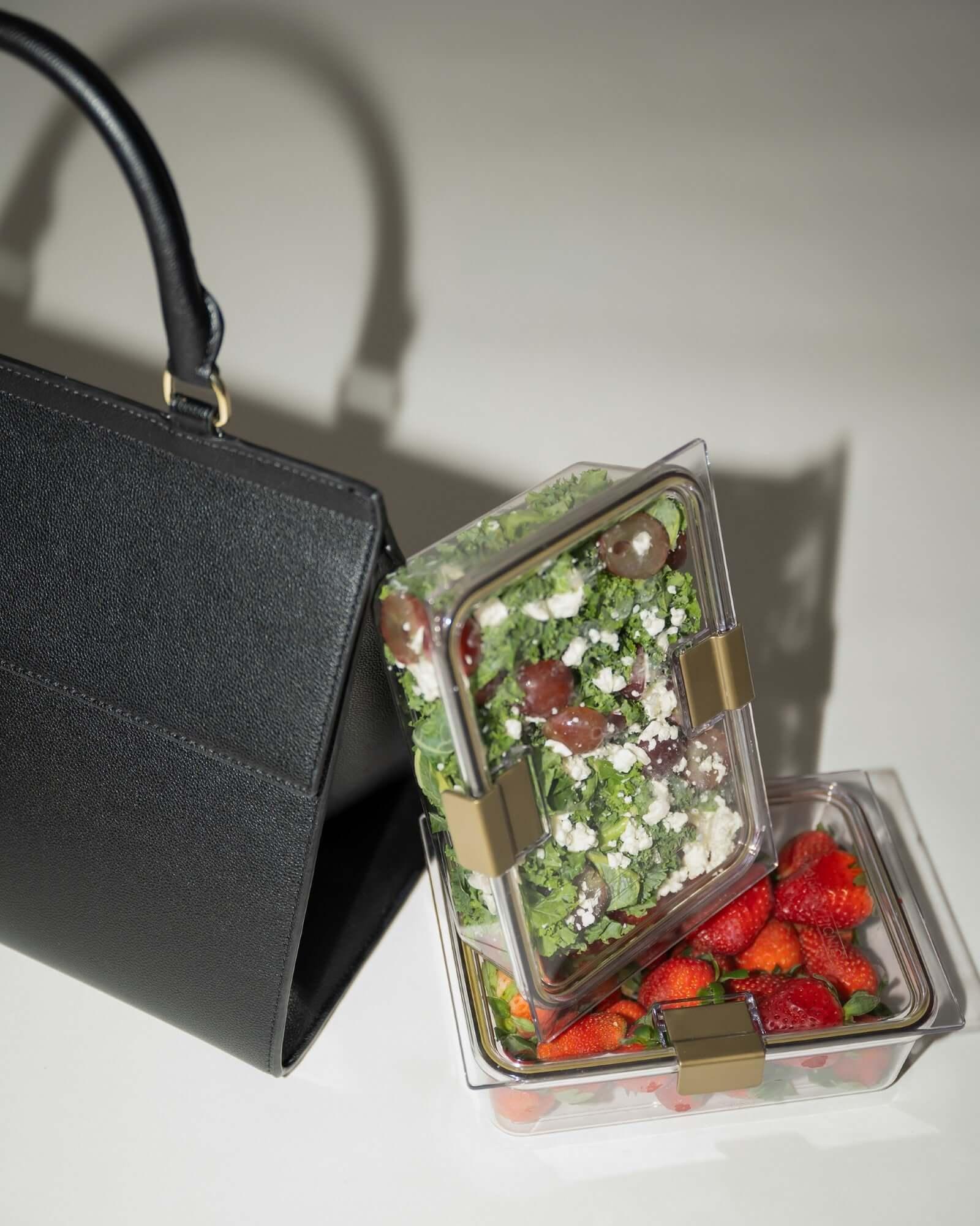 Chic black vegan leather lunch tote with kale salad and strawberries in clear meal prep containers