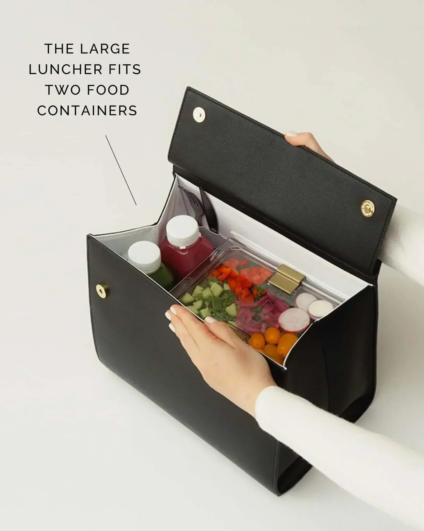 Black insulated lunch bag holding two food containers with fresh salad and drinks, perfect for work or travel.