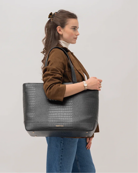 Woman holding black croc-texture vegan leather tote bag, stylish work accessory for everyday use.