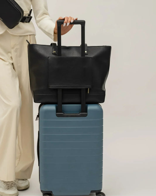 Modern Picnic black pebble tote bag secured on luggage handle, ideal for travel