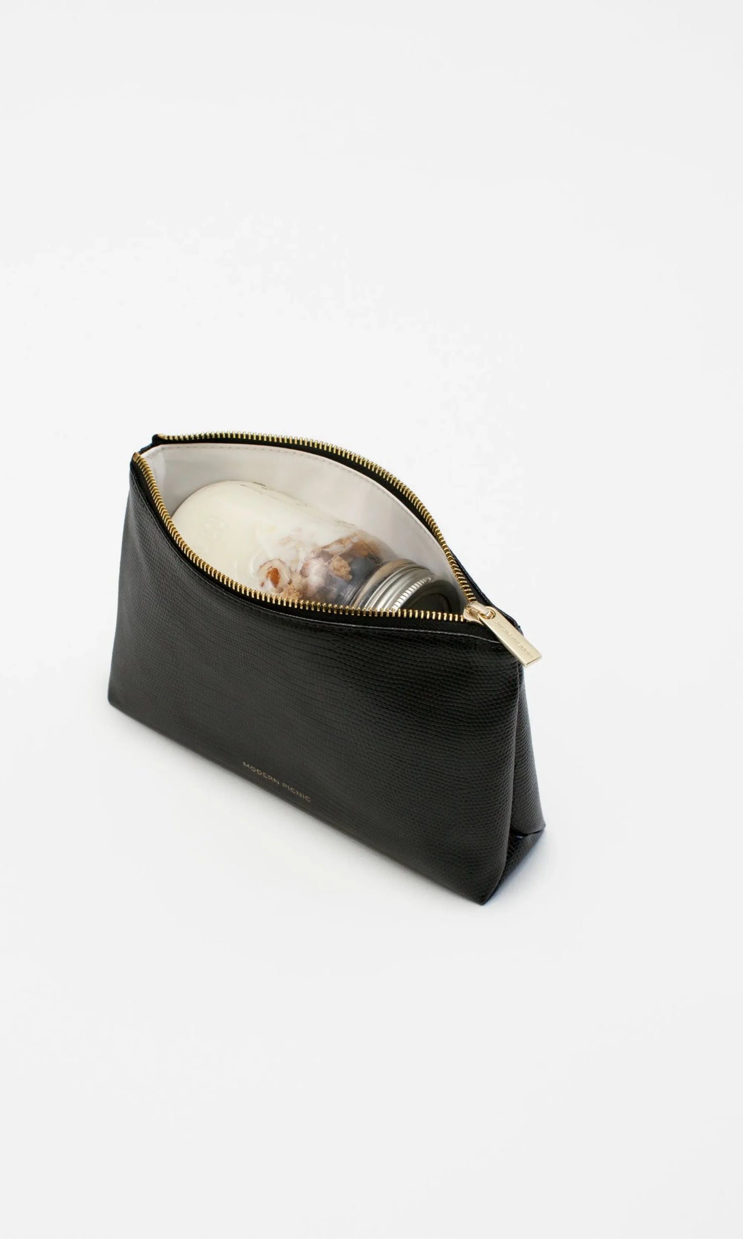 Open view of the Modern Picnic black pouch from THE SNACKER SET showing spacious interior filled with snacks and small essentials.