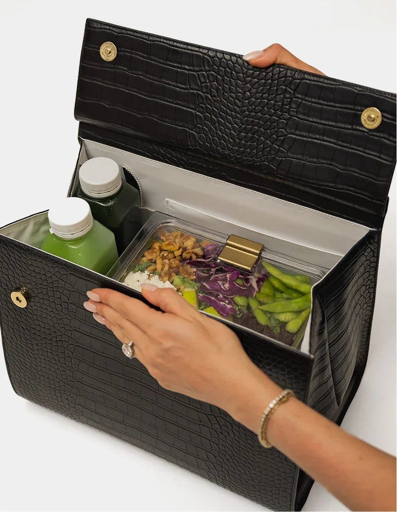 A person opens a chic black crocodile-textured insulated lunch bag containing food and drinks.