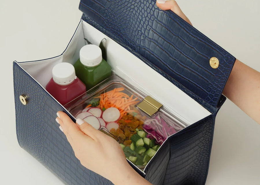 Open navy blue vegan leather insulated lunch bag containing juices and a salad container.