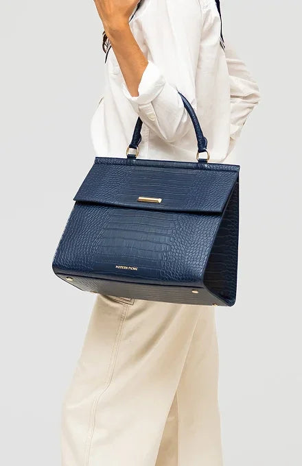 Woman carrying a navy blue vegan leather insulated lunch tote with croc-embossed texture.